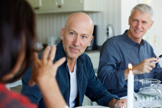 Mature men looking to female friend in dining room at home