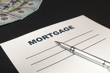 Obraz premium Mortgage with money and pen on black background.