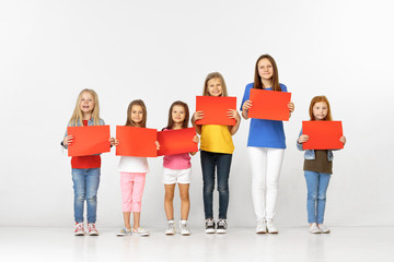 Group of happy smiling children with red empty banners isolated in white studio background. Education and advertising concept