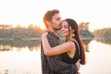 Fototapeta na wymiar Relationship, love and nature concept - Close up portrait of attractive woman and handsome man hugging on the background of the lake