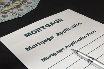 Mortgage with money and pen on black background.