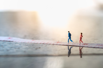 Sport and fitness concept. Male and Female runner miniature figures running on measurement tape...