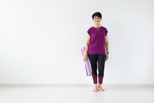 Yoga, Peopel Concept - Middle Age Woman Holding Mat After A Yoga Class On White Background With Copy Space