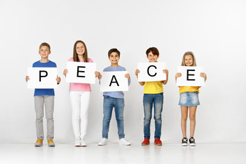 Fototapeta premium No war for peace. Group of happy smiling children with a white banners making word isolated in studio background. Education, advertising and social rights concept.