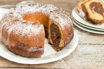 Marble cake with powdered sugar on top, wooden background