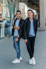 beautiful and attractive guy is standing in the city, posing. near the mirror building. walk around the city . communication. meeting friends.