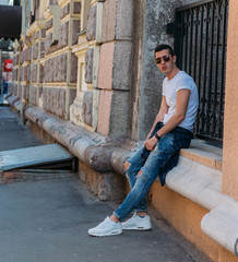 Attractive, sexy guy sits on the street in sunglasses. self-confidence, flatulence and arrogance....
