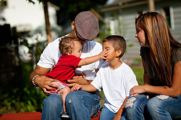 Happy Young Family Sitting Together Outside - Color Portrait