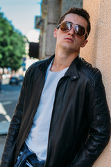 Attractive, sexy guy standing on the street in sunglasses. self-confidence, flatulence and arrogance. model, posing, portrait of a young man