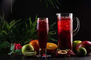 Lemonade blueberry - blackberry in a jug and a glass and fruit on dark wooden background