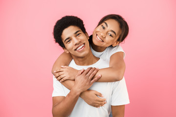 Man giving piggyback ride to his girlfriend on pink background