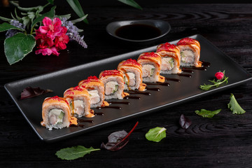 Set sushi rolls on a black rectangular plate on a dark wooden background