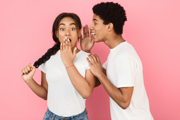 Boyfriend whispering interesting gossip to surprised girl