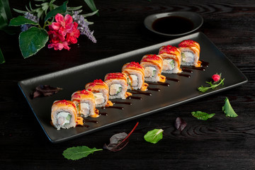 Set sushi rolls on a black rectangular plate on a dark wooden background