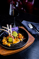 Close up of lamb chops with vegetables with a sauce of caramel, pepper and spices in a restaurant setting.