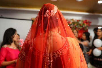 Naklejka premium Beautiful Indian bride in traditional outfit red dupatta and red blouse, beautiful hair bun with white roses
