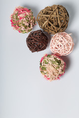 Candle white in color among the decorative balls, woven from natural materials. On a white background.