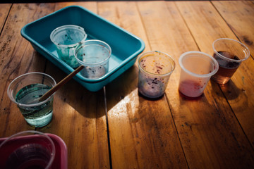 Leftover water color in plastic cup, kids painting activity.