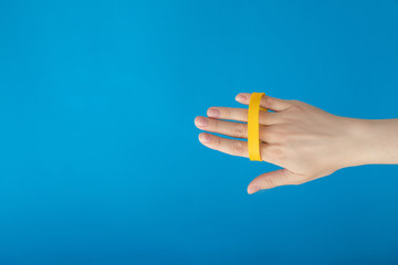 Female hand with empty yellow bracelet on blue background. Music festival branding empty wristband design. Clear sweat band mock up design.