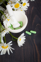 Chamomile flowers and green phytotherapeutic capsules.