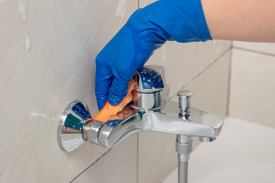 Close-up Of The Shower Faucet And Shower Head Cleaning Process From Lime Scale, White Chalk Sediment And Stains Using A Commercial Soap Scum Remover. Bathroom Cleaning And Disinfection, Cleanup