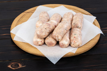 Fresh raw sausage on the wooden background