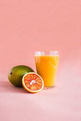 Glasses of mango, orange juice on pink background.