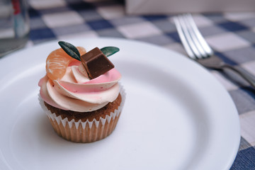 Strawberry cupcakes on white plate, tangerine and chocolate