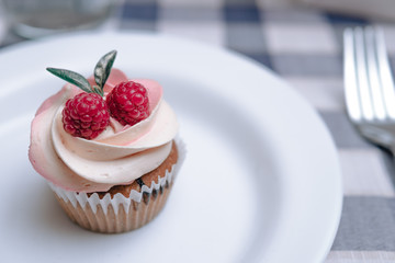 Strawberry cupcakes on white plate, table fork. composition with raspberry berries and green leaves