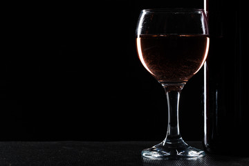  wine bottle and wine glass in a black background