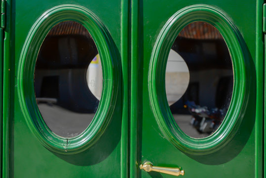 Puertas traseras verdes con ventanillas ovaladas de un coche antiguo