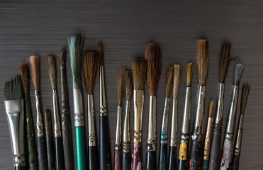 Old used small paint brushes on brushed metal texture background