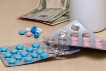 Blue and pink pills in the package and dollars on the table