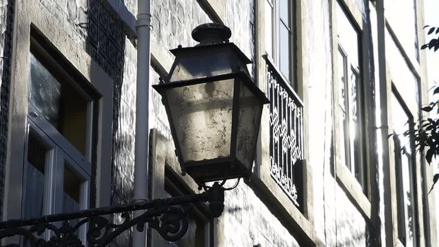 Dirty street light near facade of old building in sunny weather in Lisbon