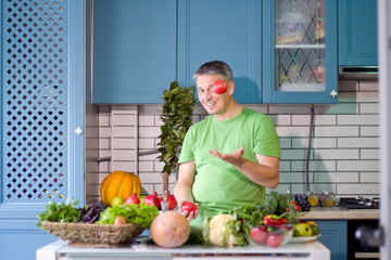 A man in the kitchen prepares vegetarian dishes. Vegetables , ready for cooking.