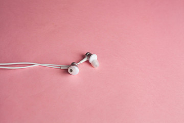 White headphones on a pink background, top view, copyspace.