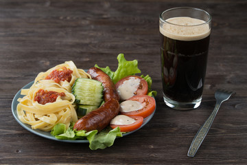 Macaroni, vegetables and fried sausages with dark beer