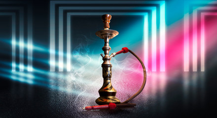 Hookah smoking on a dark abstract background. Hookah on a concrete background, neon lights, blurred...