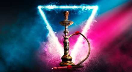 Hookah smoking on a dark abstract background. Hookah on a concrete background, neon lights, blurred...