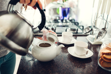 Woman pouring tea into ceramic cup at table