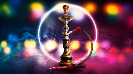 Hookah smoking on a dark abstract background. Hookah on a concrete background, neon lights, blurred night lights, bokeh