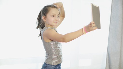 Cute little girl in front of the camera tablet. Girl shooting a video. Children's blog. Teen blogger. stream video for blog. Children's channel. Popular applications for success and popularity