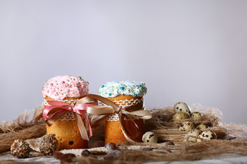 Two cakes or cupcakes with blue and pink icing on a gray or white background. The end of the Easter holiday. Still life concept
