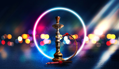 Hookah smoking on a dark abstract background. Hookah on a concrete background, neon lights, blurred...