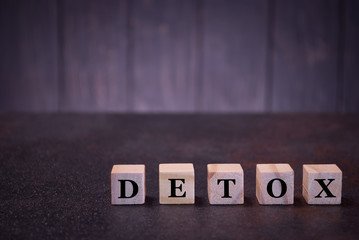 The word detox on wooden cubes, on a dark background, symbols signs