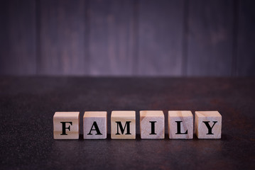 Fototapeta na wymiar The word family on wooden cubes, on a dark background, symbols signs