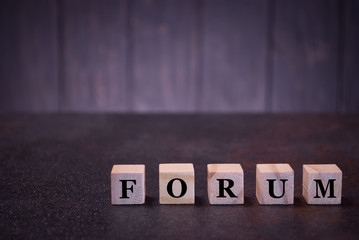 The word forum on wooden cubes, on a dark background, symbols signs