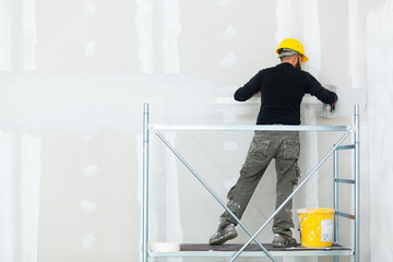 worker plastering gypsum board wall. - obrazy, fototapety, plakaty