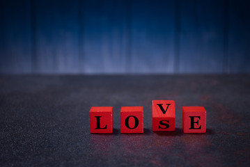 The word love lose on red wooden cubes, on a dark background, light wooden cubes signs