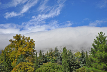 Mountain peaks of Crimean mountains covered with mist on a background of blue sky and sea